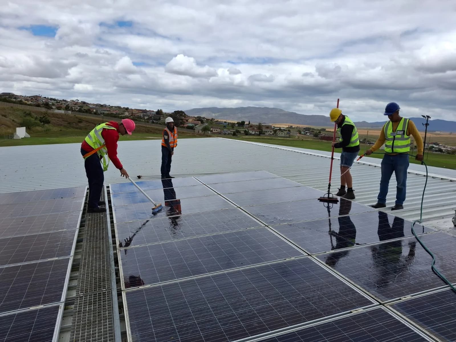 Technicians cleaning a large commercial rooftop solar array in Cape Town
